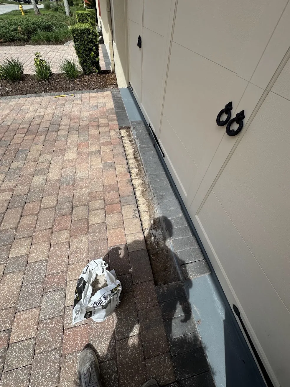 Paver walkway beside a garage door during cleaning