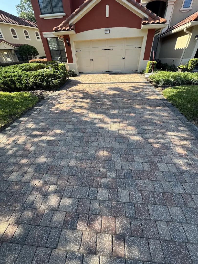 Paver driveway restored to its original color in front of a two-story home